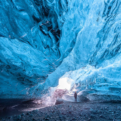 Tourist standing in an ice cave in Vatnajökull glacier Iceland